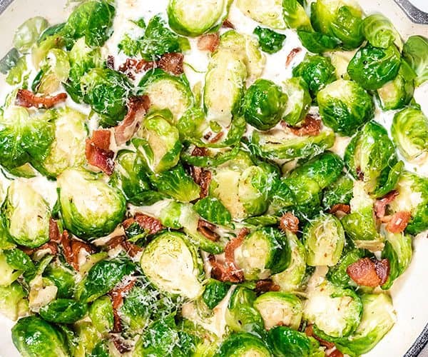 A pan with brussels sprouts and bacon in a cream sauce.