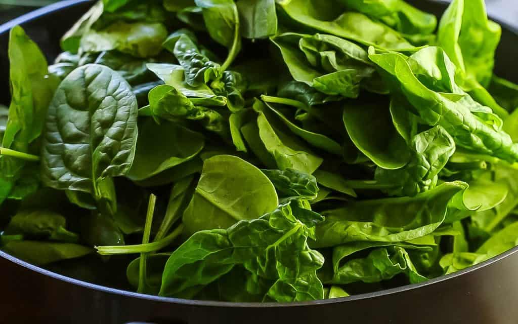 fresh spinach added to the pan with the sauce