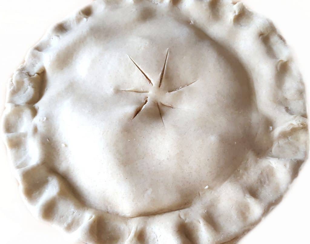 a raw apple pie with the top dough added to it