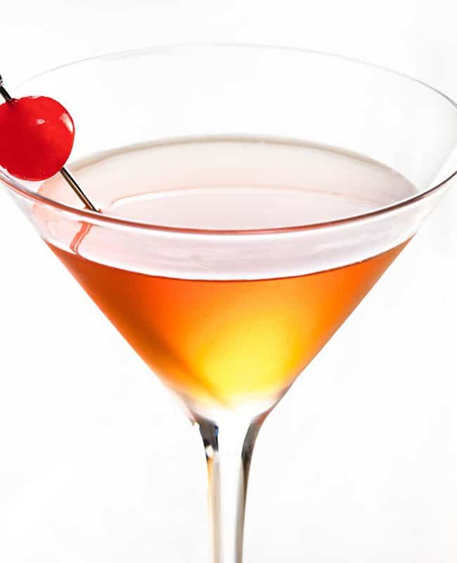 a cocktail glass with manhattan drink and a cherry