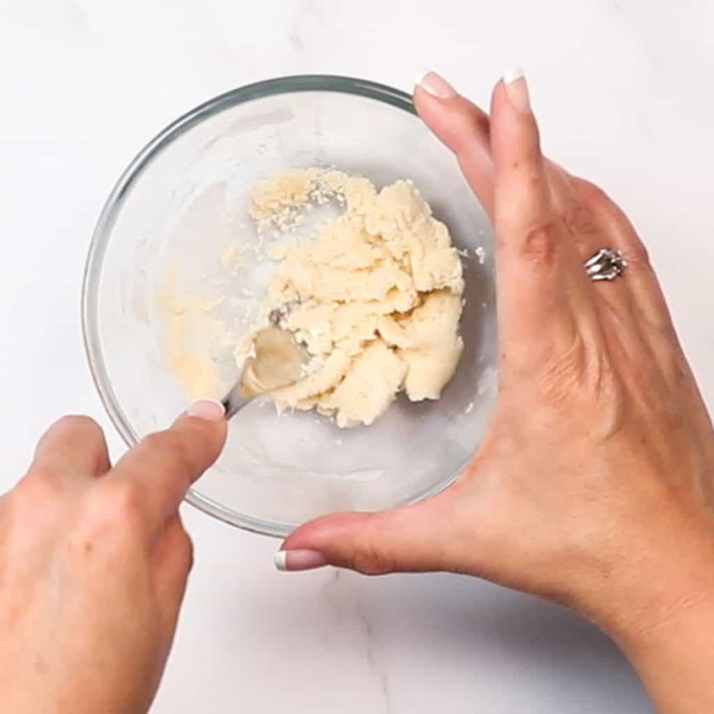 flour and butter being mixed in a glass bowl