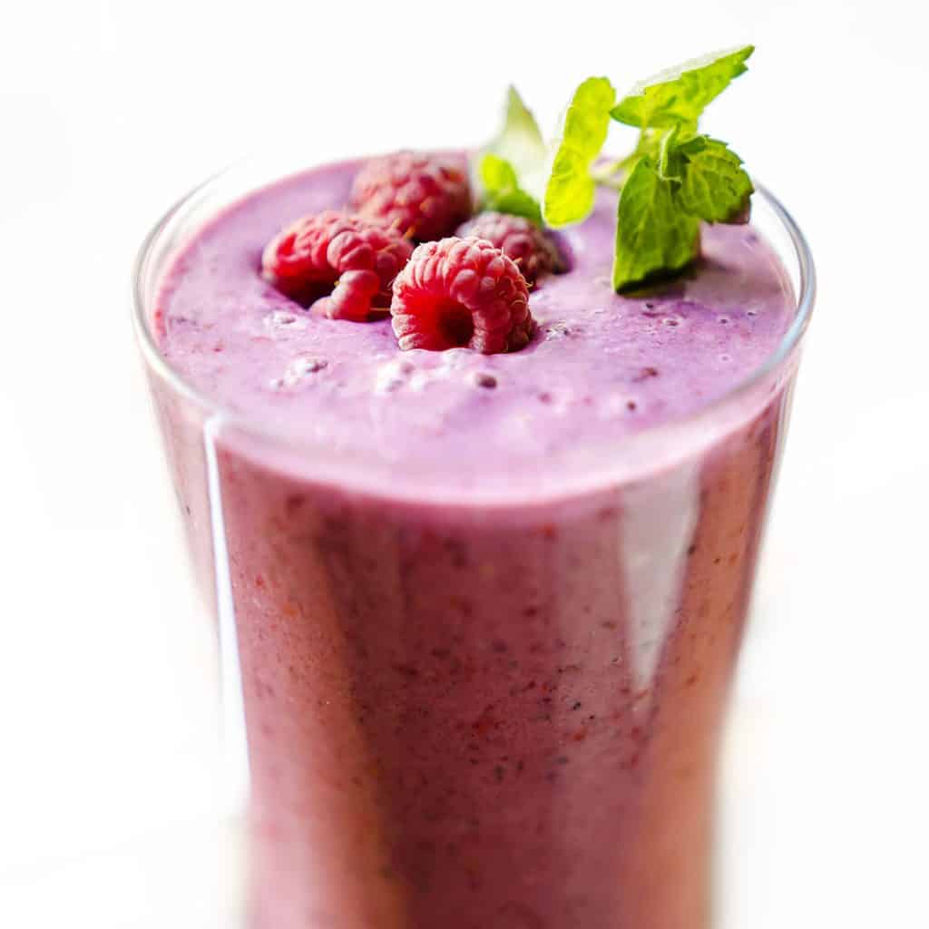 raspberry smoothie topped with raspberries and a sprig of mint for decoration