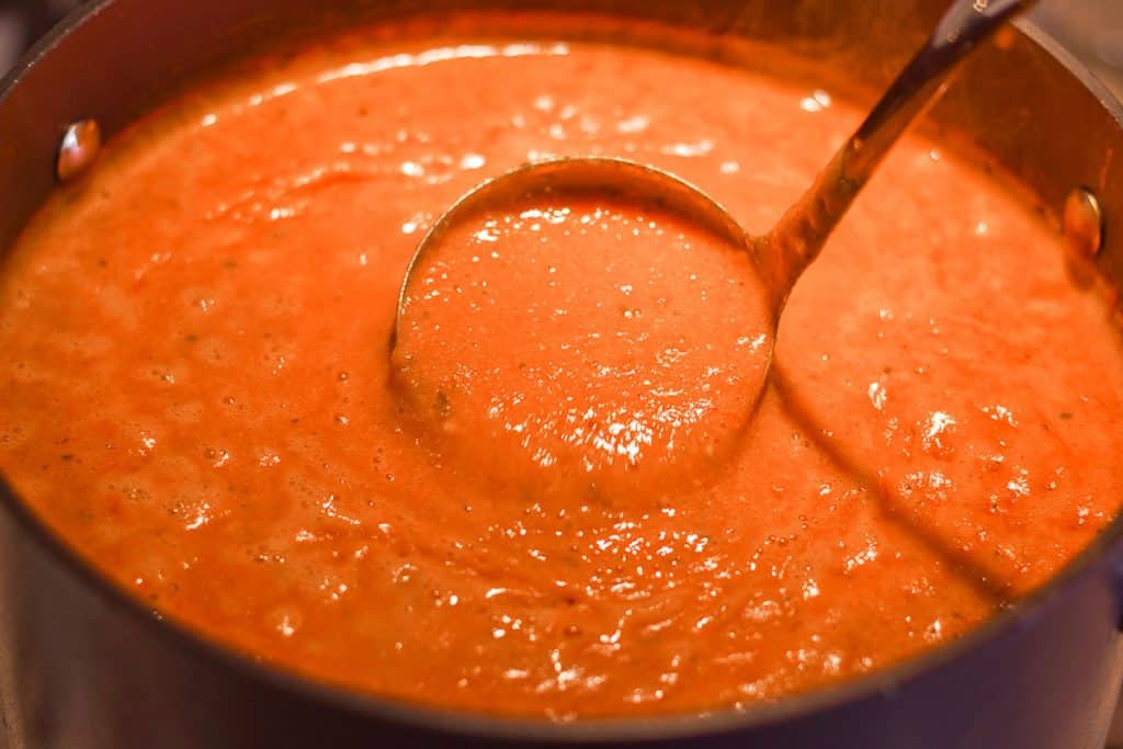 a spoon serving tomato soup