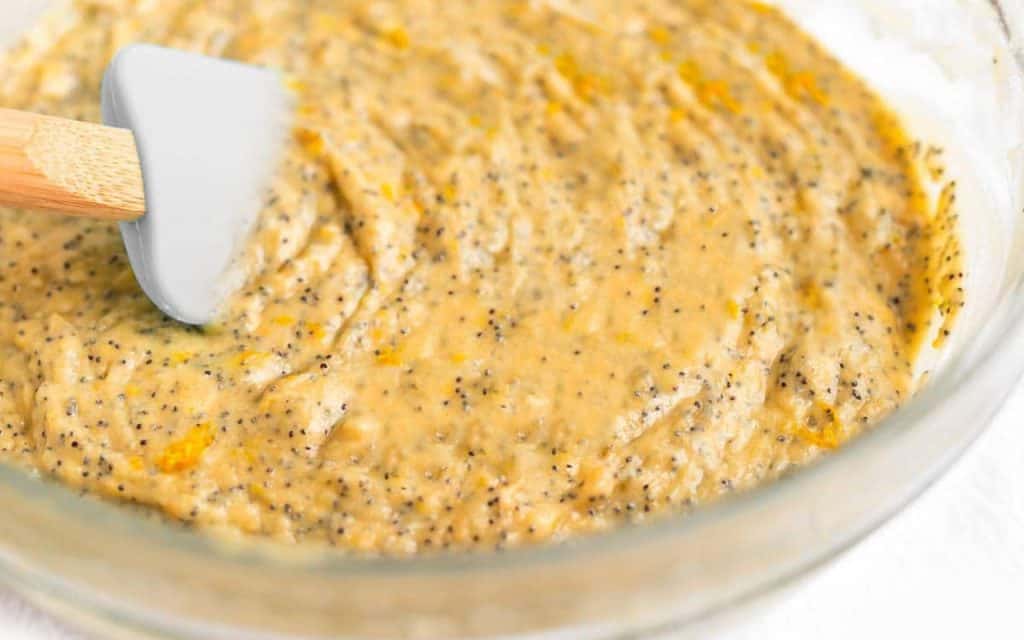 orange cake batter with poppy seeds mixed in