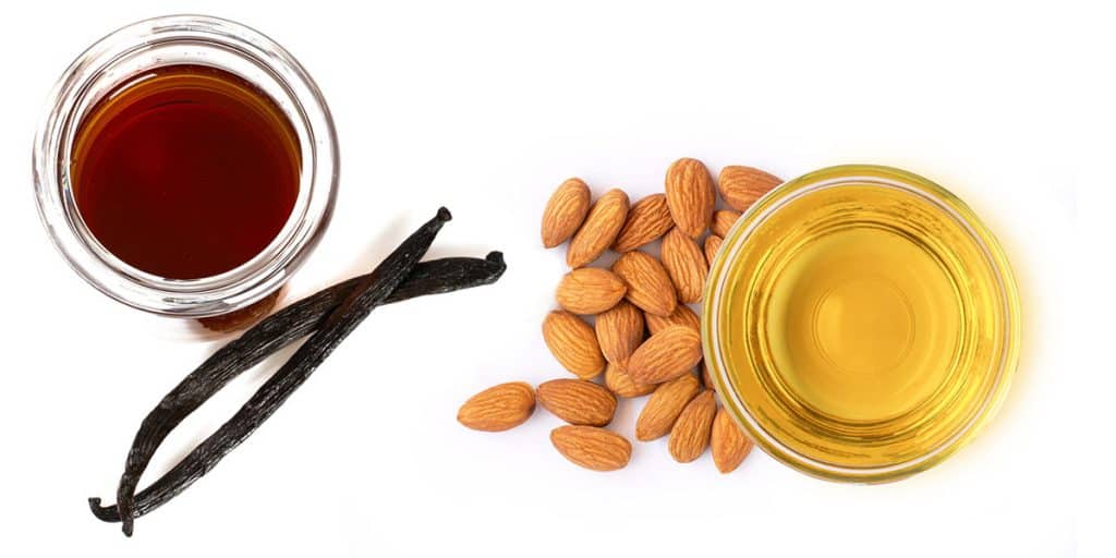 a bowl of vanilla extract with vanilla pods and a bowl of almond extract with almonds