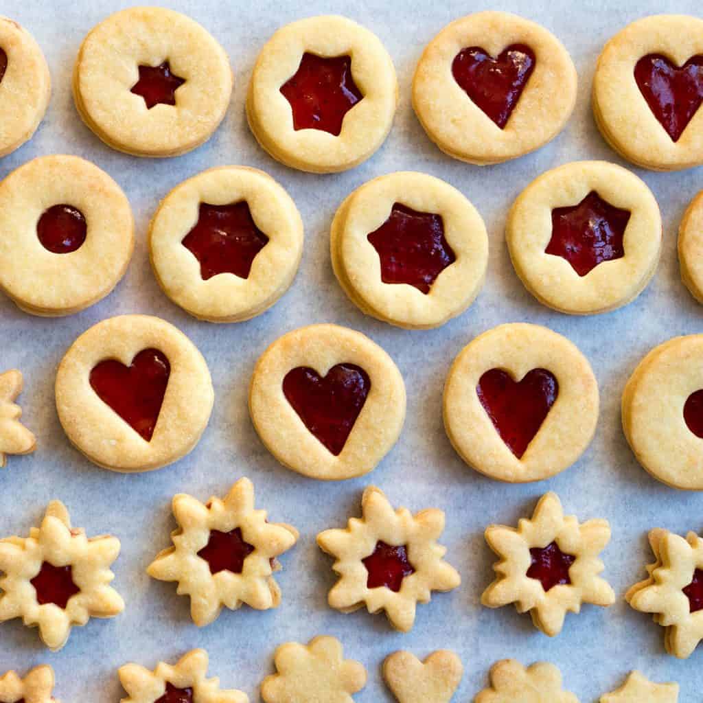 Traditional Linzer cookies filled with jam on parchment paper