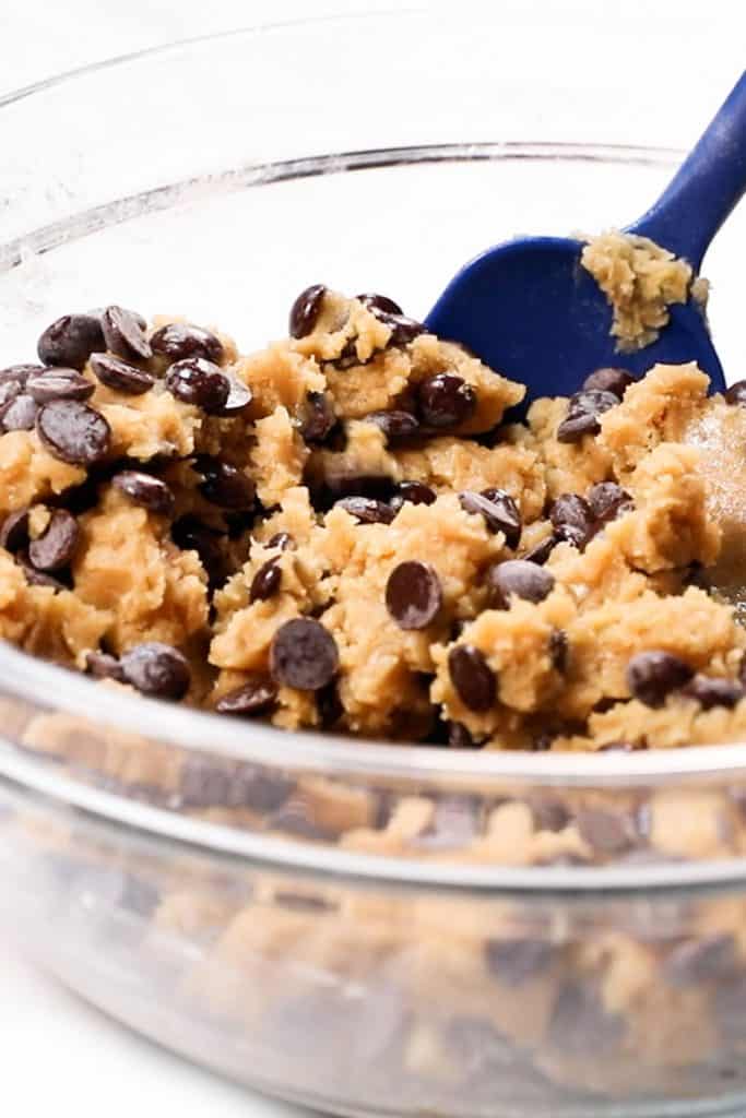 chocolate chips being mixed into cookie dough