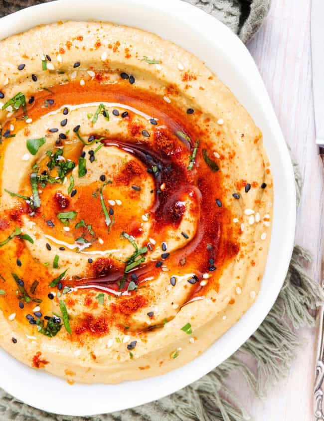 A bowl of creamy Baba Ghanouj, garnished with paprika, sesame seeds, and fresh herbs.