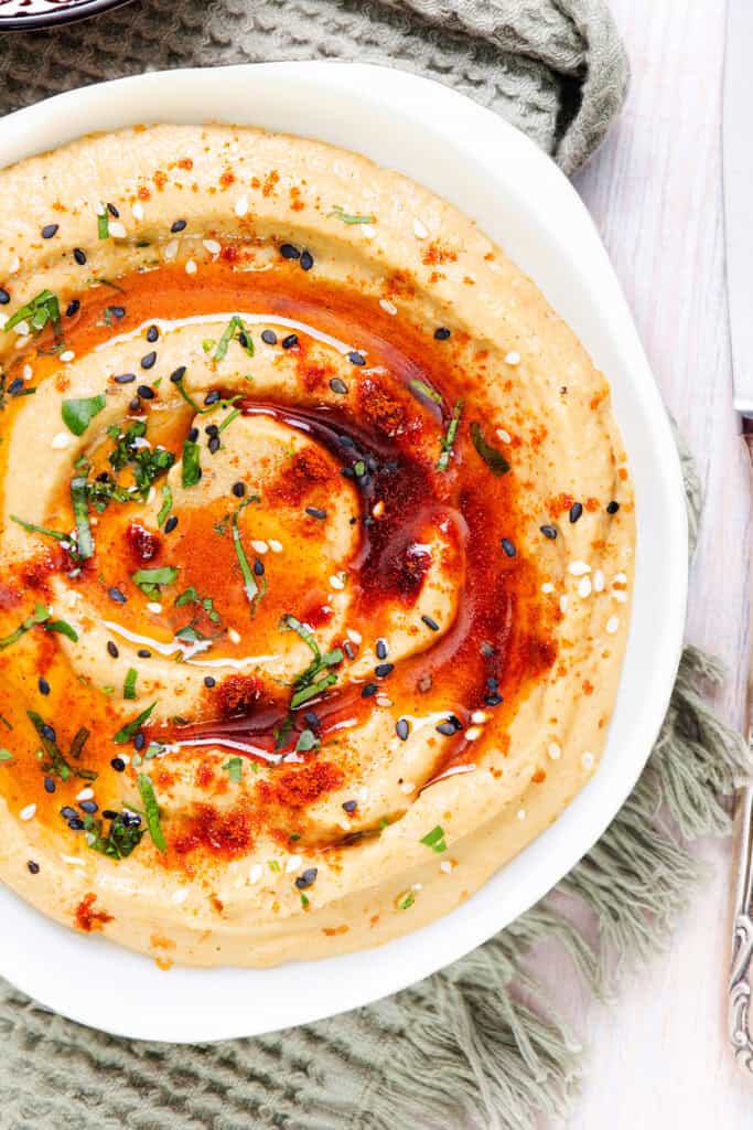 A bowl of creamy Baba Ghanouj, garnished with paprika, sesame seeds, and fresh herbs.