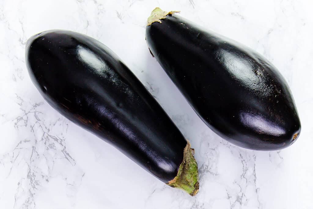 Two eggplant on a kitchen counter.