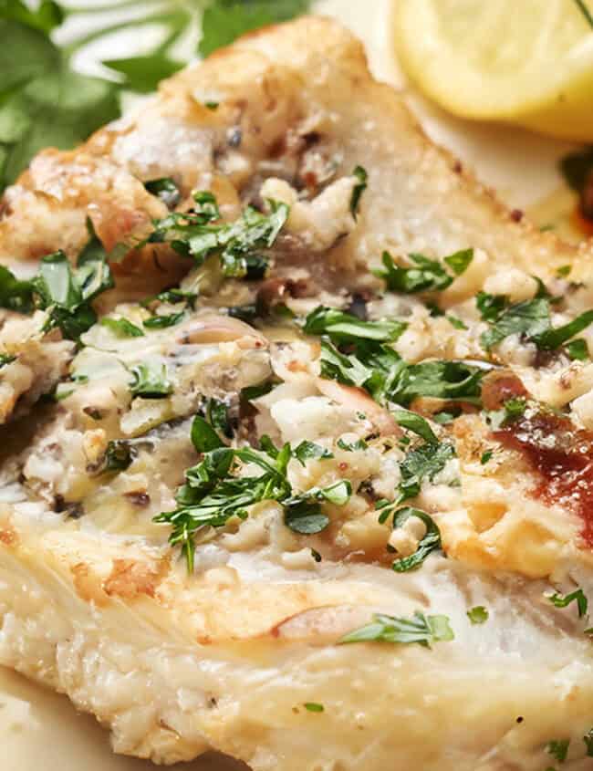 A close up image of a seared cod filet in a garlic butter sauce.