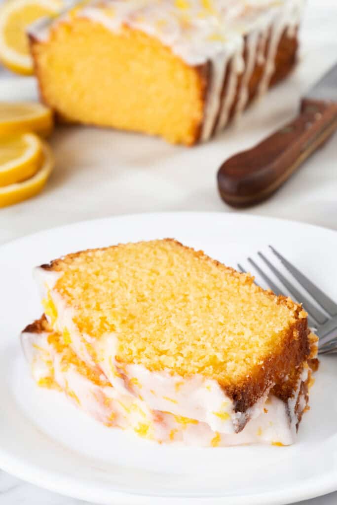 Slices of glazed lemon pound cake with the cake in the background.