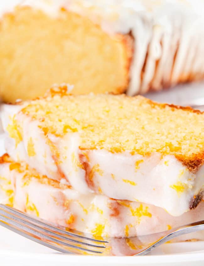 A sliced lemon pound cake with icing and lemon zest.