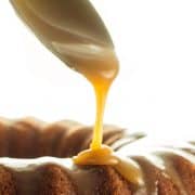 a spoon adding caramel glaze to a cake