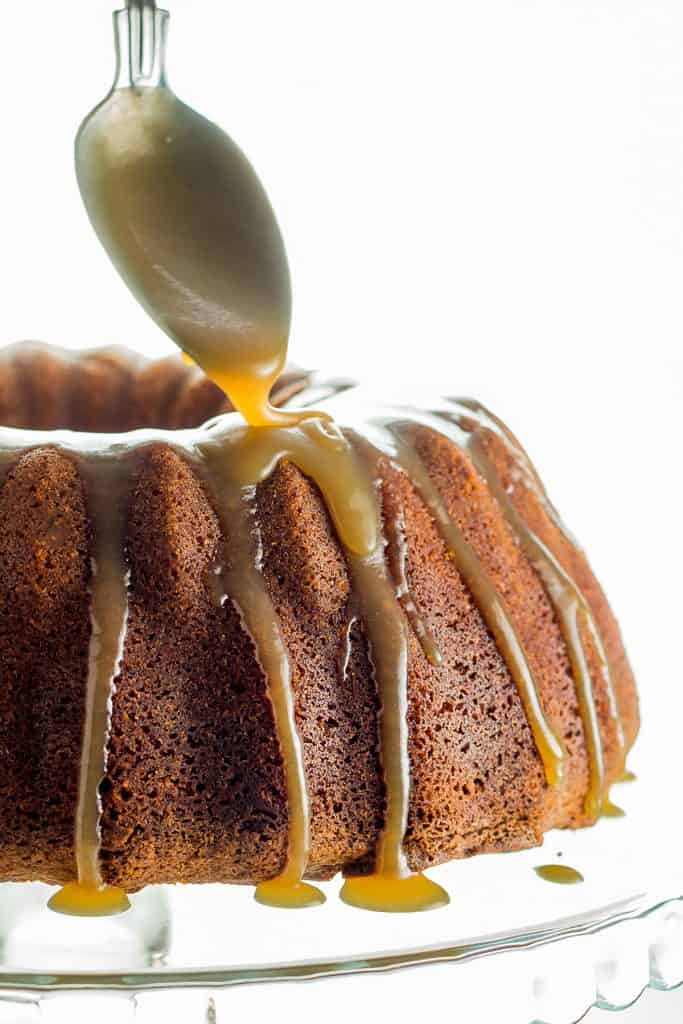 caramel glaze being pored onto a cake with a spoon