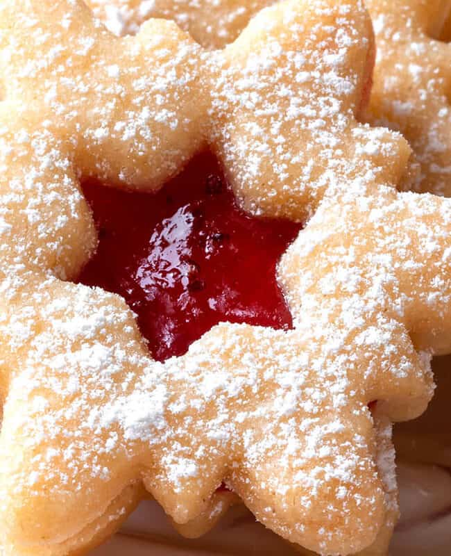 a snowflake xmas cookie filled with jam and dusted with powdered sugar