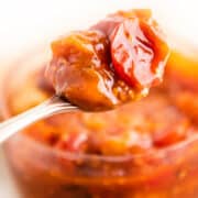 a jar of tomato jam with a spoonful