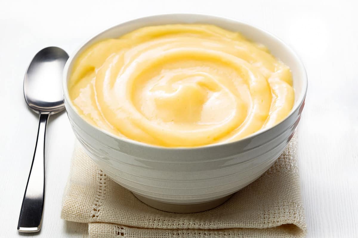 a white bowl filled with pastry cream that's swirled on top