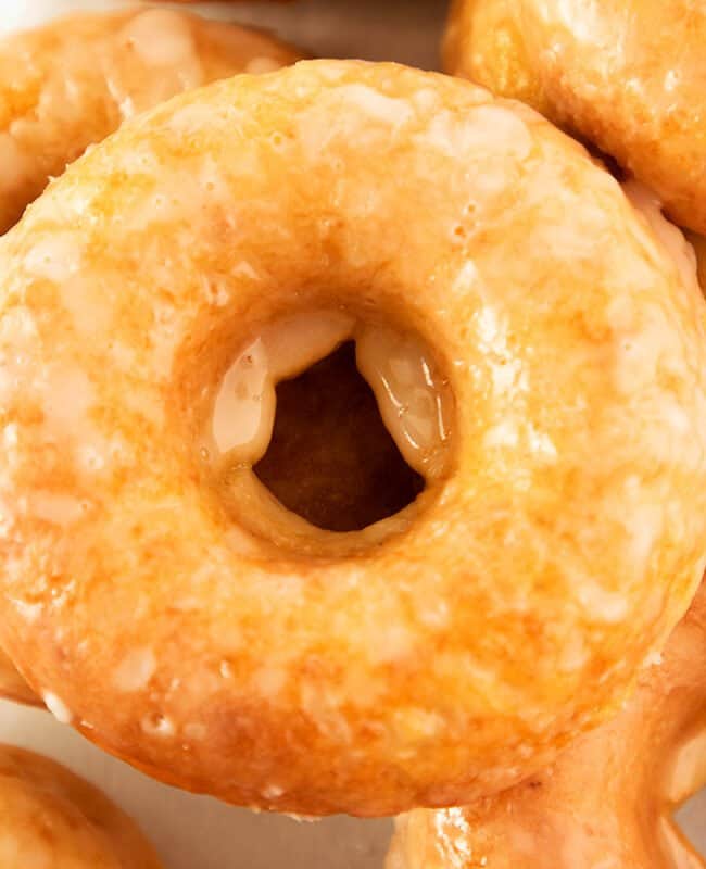 A close up of a pile of glazed cake donuts