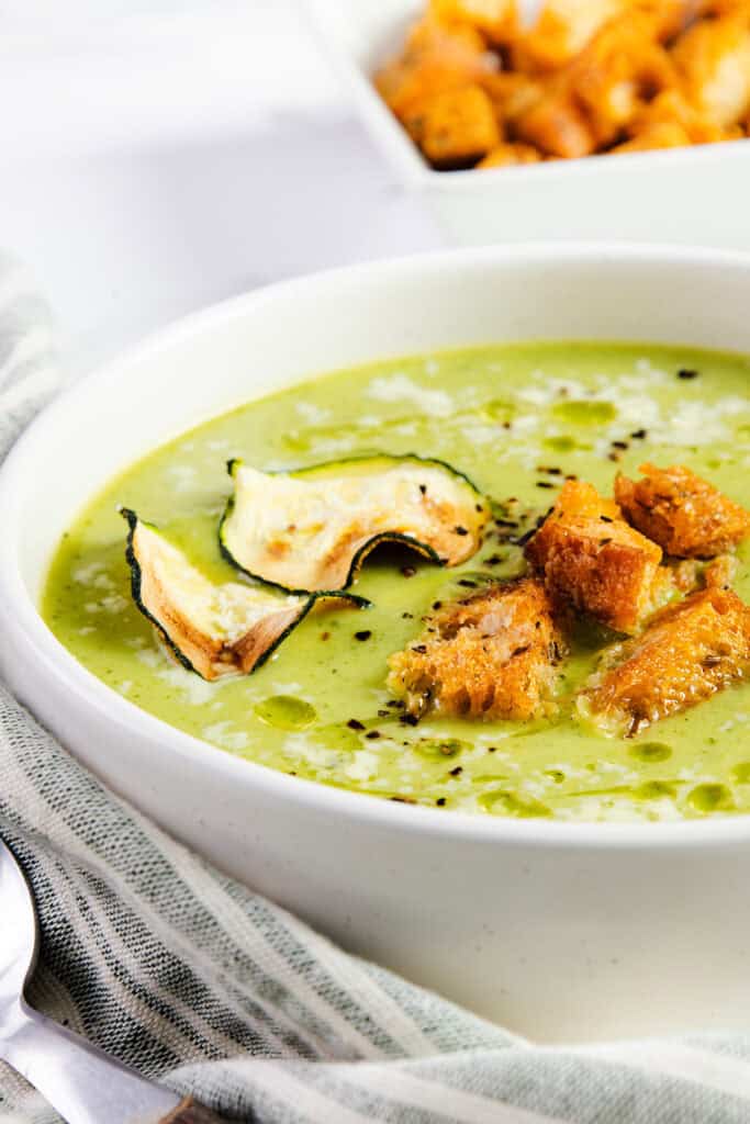 A close up image of Zucchini Soup topped with Zucchini chips and croutons.