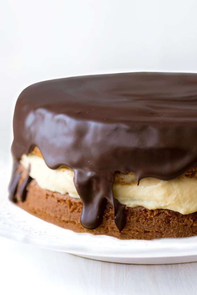 a close up of a vanilla cake filled with custard and covered in chocolate glaze