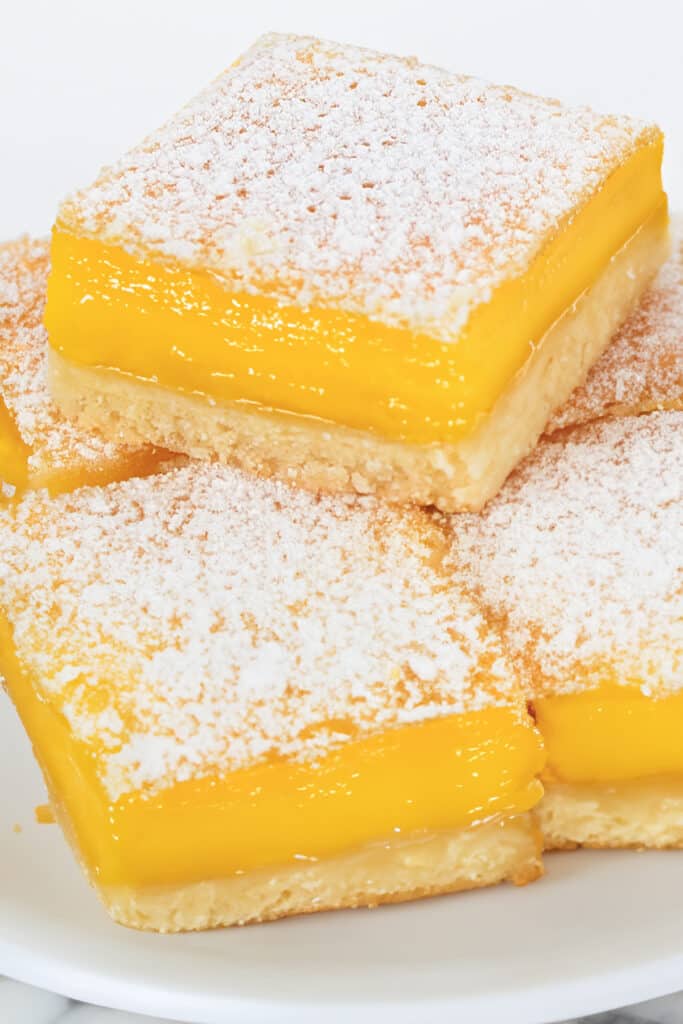 A pile of lemon squares on a plate.