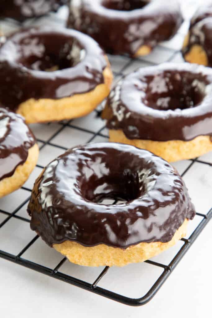 Chocolate frosted donuts cooling on a whire rack