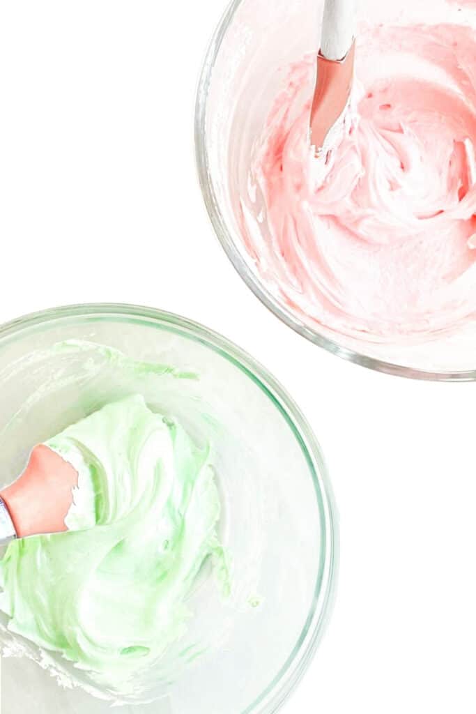 a bowl of green frosting and a bowl of pink frosting