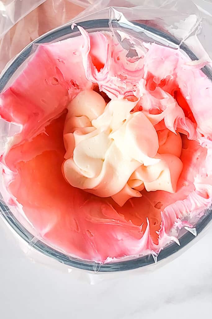 white and pink frosting in a piping bag