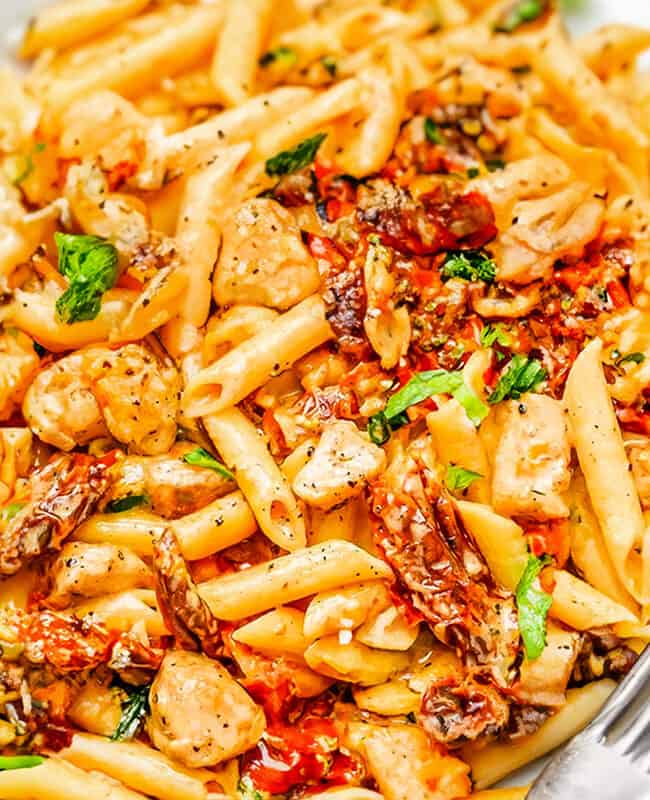 a white plate with Chicken Sundried Tomato Pasta and a fork.