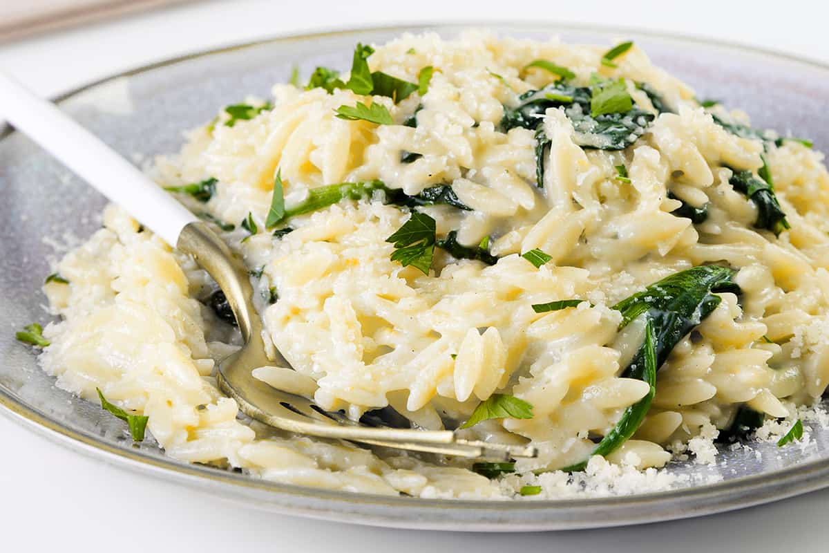 ose up omage of Parmesan Lemon Orzo Pasta in a bowl with a serving spoon.