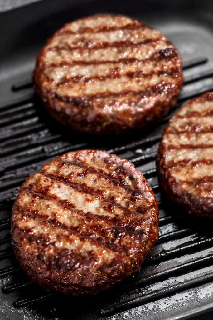 three hamburgers made with The Best Hamburger Recipecooking on a grill pan