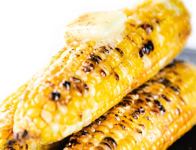 Three ears of Grilled Corn On The Cob topped with a pad of butter