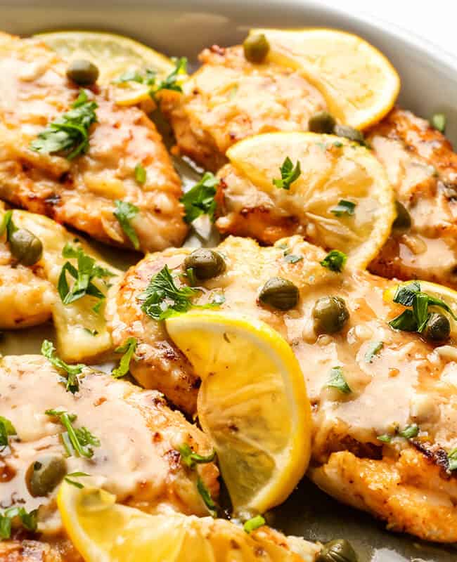 A plate of Fish Piccata garnished lemon and capers.