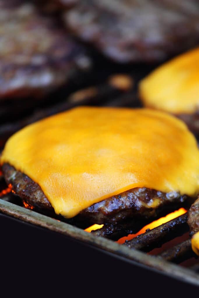 a cheeseburger cooking on a grill