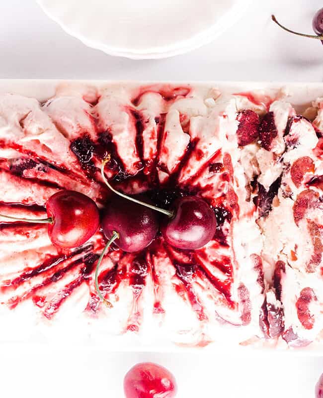 an over head shot of cherry semifreddo topped with cherry jam and fresh cherries and a jam covered spoon