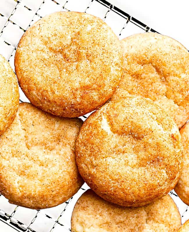 Snickerdoodles stacked on a cooling rack.