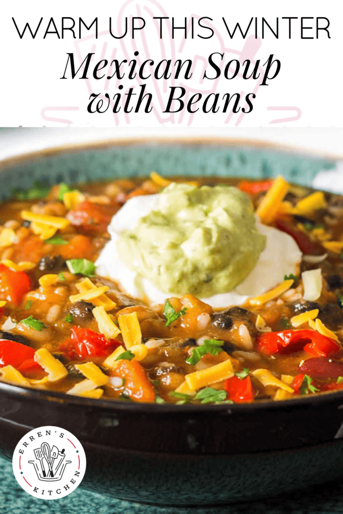 A bowl full of Mexican soup with beans and rice, shredded cheese, and a dollop of guacamole and sour cream in the center.