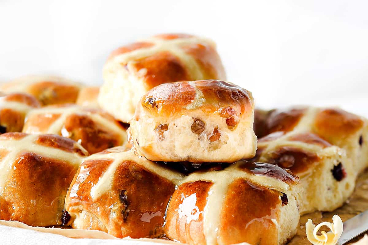 a pile of fresh hot cross buns with a clear glaze on top
