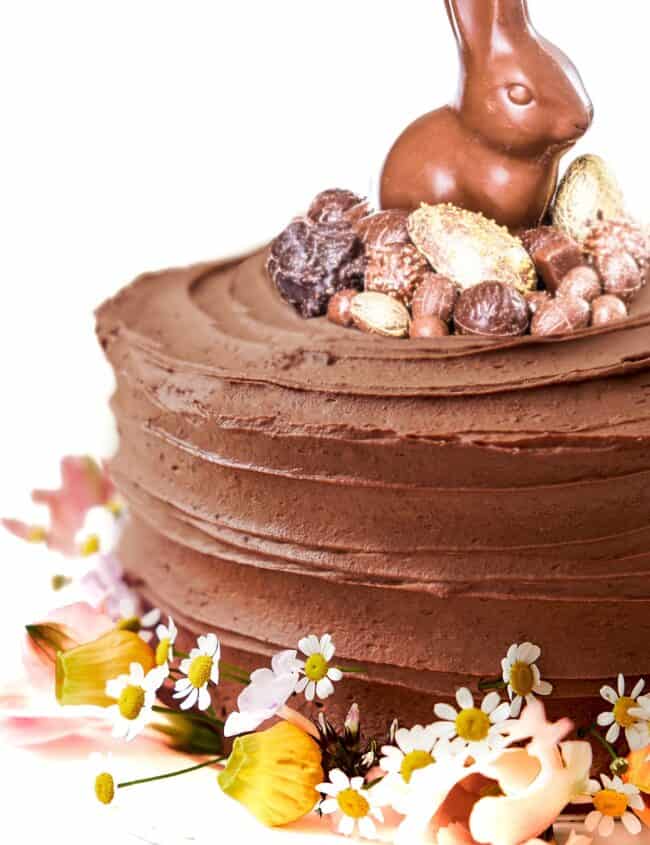 A vertical closeup shot of a chocolate cake decorated with flowers and easter candy