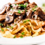 a close up image of Beef Stroganoff made up of Beef and mushrooms in a creamy Stroganoff sauce over noodles.