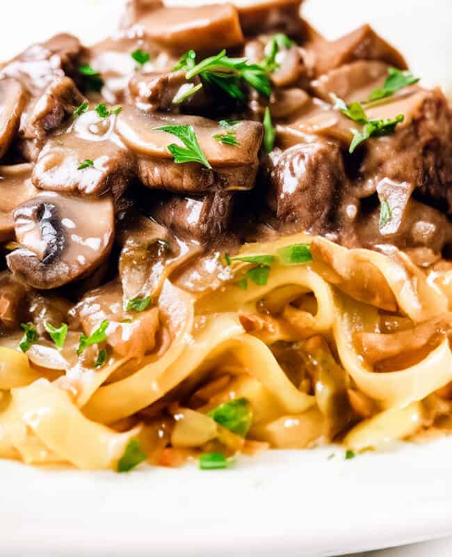 a close up image of Beef Stroganoff made up of Beef and mushrooms in a creamy Stroganoff sauce over noodles.