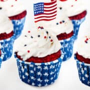 a group of 4th of July Cupcakes topped with American flags and red, white, and blue, decoration.