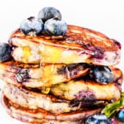 blueberry pancakes dripping with syrup and topped with fresh blueberries