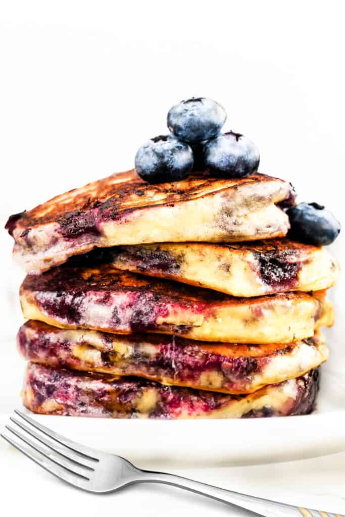 a stack of blueberry pancakes on a plate with a fork