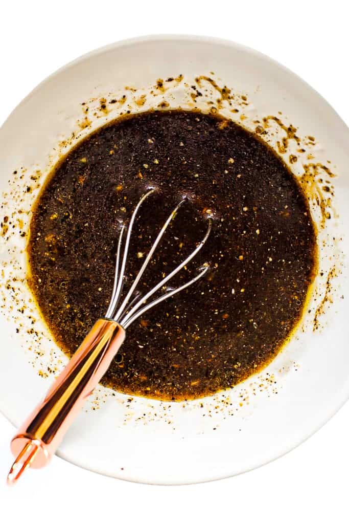 a bowl of marinade mixed with a whisk