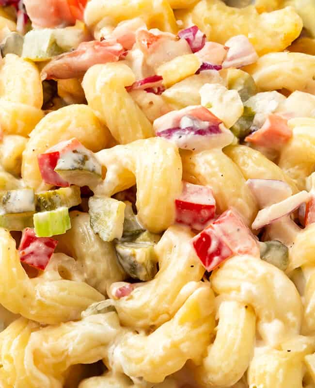 a close up image of a bowl of Amish Macaroni Salad with creamy sauce and chopped vegetables