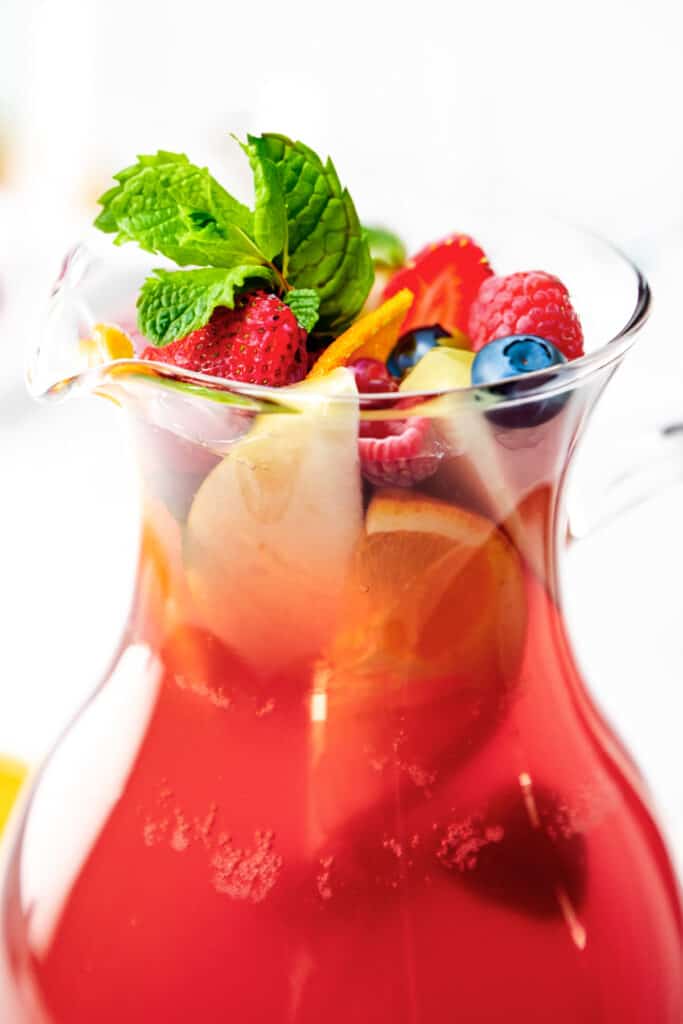 a close up image of a jug of Rosé Sangria topped with fresh fruit and mint.