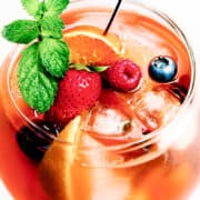 a close up image of a glass of Rosé Sangria with fresh fruit, mint and a cocktail stick in the glass.