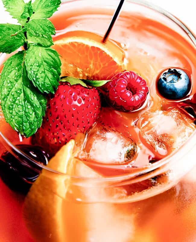 a close up image of a glass of Rosé Sangria with fresh fruit, mint and a cocktail stick in the glass.